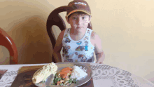 a little boy wearing a hat that says buffet on it sits at a table with a plate of food