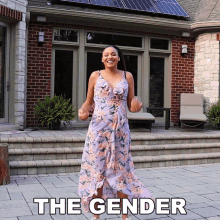 a woman in a floral dress is standing in front of a brick house with the words the gender written on the ground