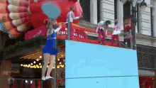 a woman in a blue dress is standing on a blue wall in front of a sign that says holiday