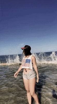 a woman wearing an american flag tank top stands in the water