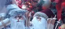 two santa claus figurines are sitting next to a christmas tree