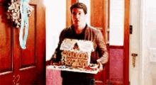 a man is holding a gingerbread house on a tray .