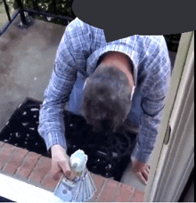 a man in a plaid shirt holds a bunch of money in his hand