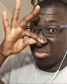 a man wearing glasses is making a funny face with his hand