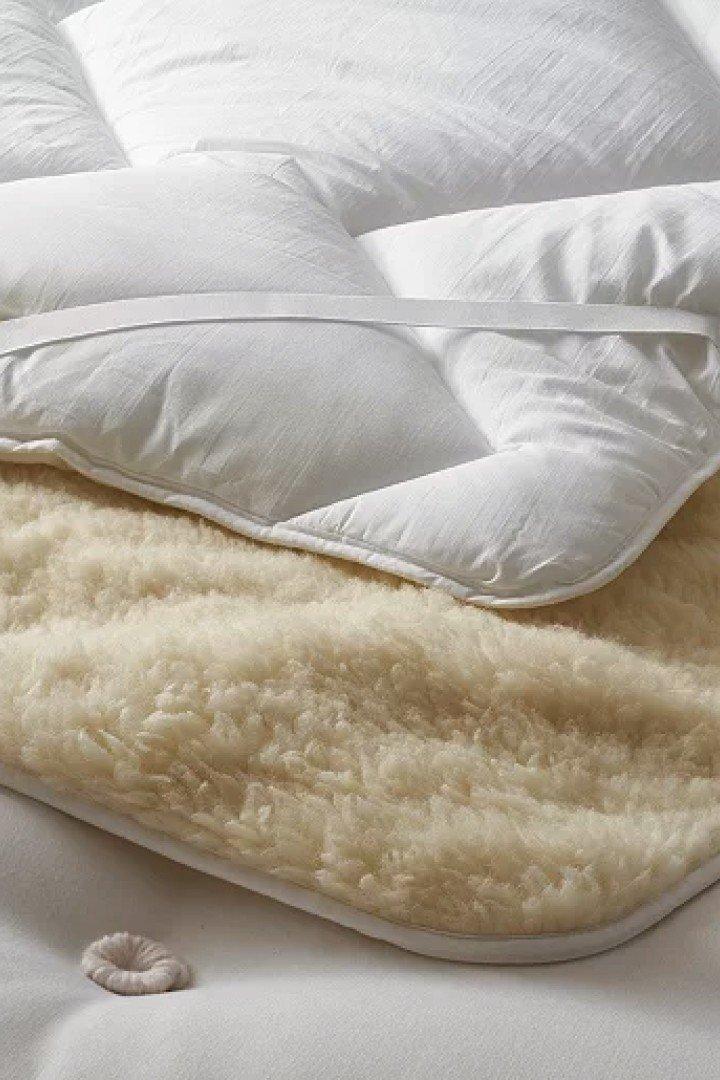 a close up of a white blanket with a white pillow on top