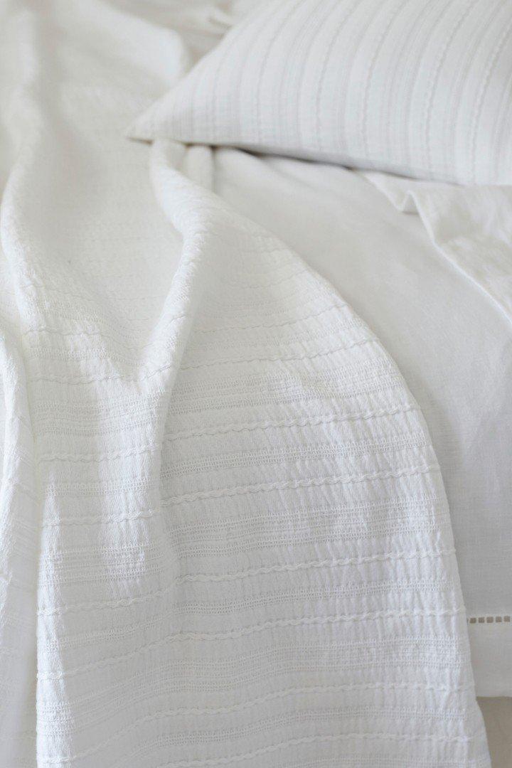 a white bed with a white comforter and pillows on it