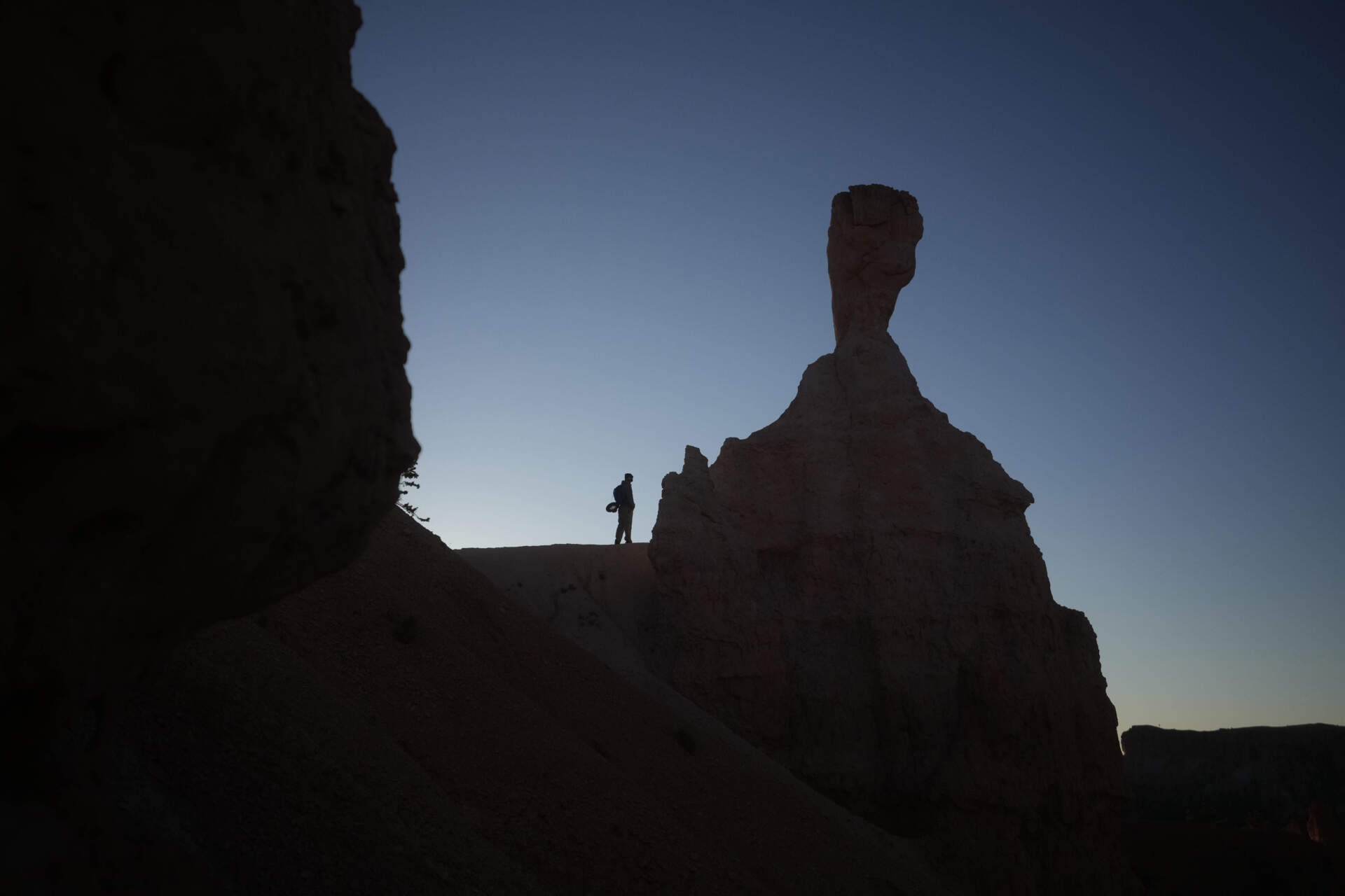 A man stands on a lookout point at sunrise in Bryce Canyon National Park, Utah, before a rare 