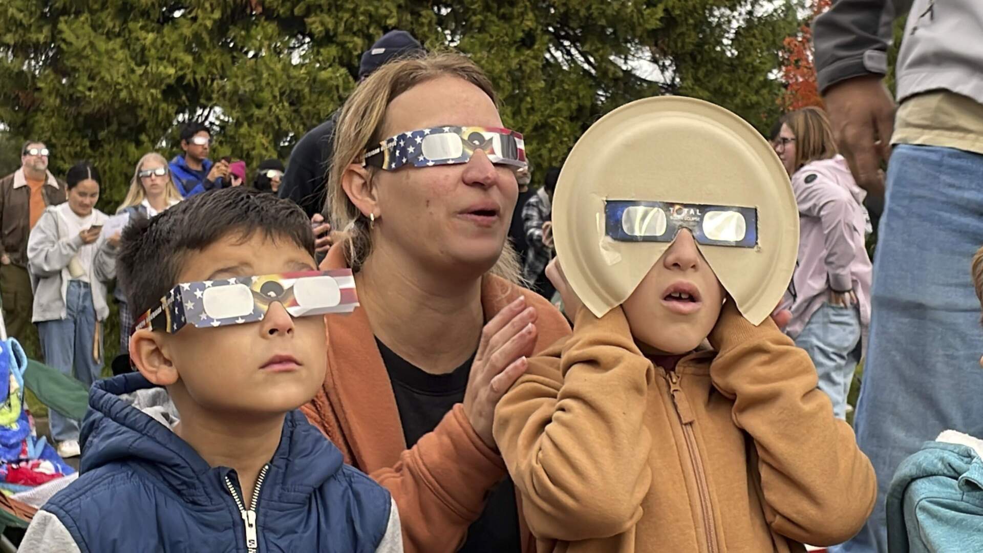 Samia Harboe, her son Logan and her friend's son wear eclipse glasses during totality of the annular solar eclipse in Eugene, Ore., on Saturday, Oct. 14, 2023. (Claire Rush/AP)