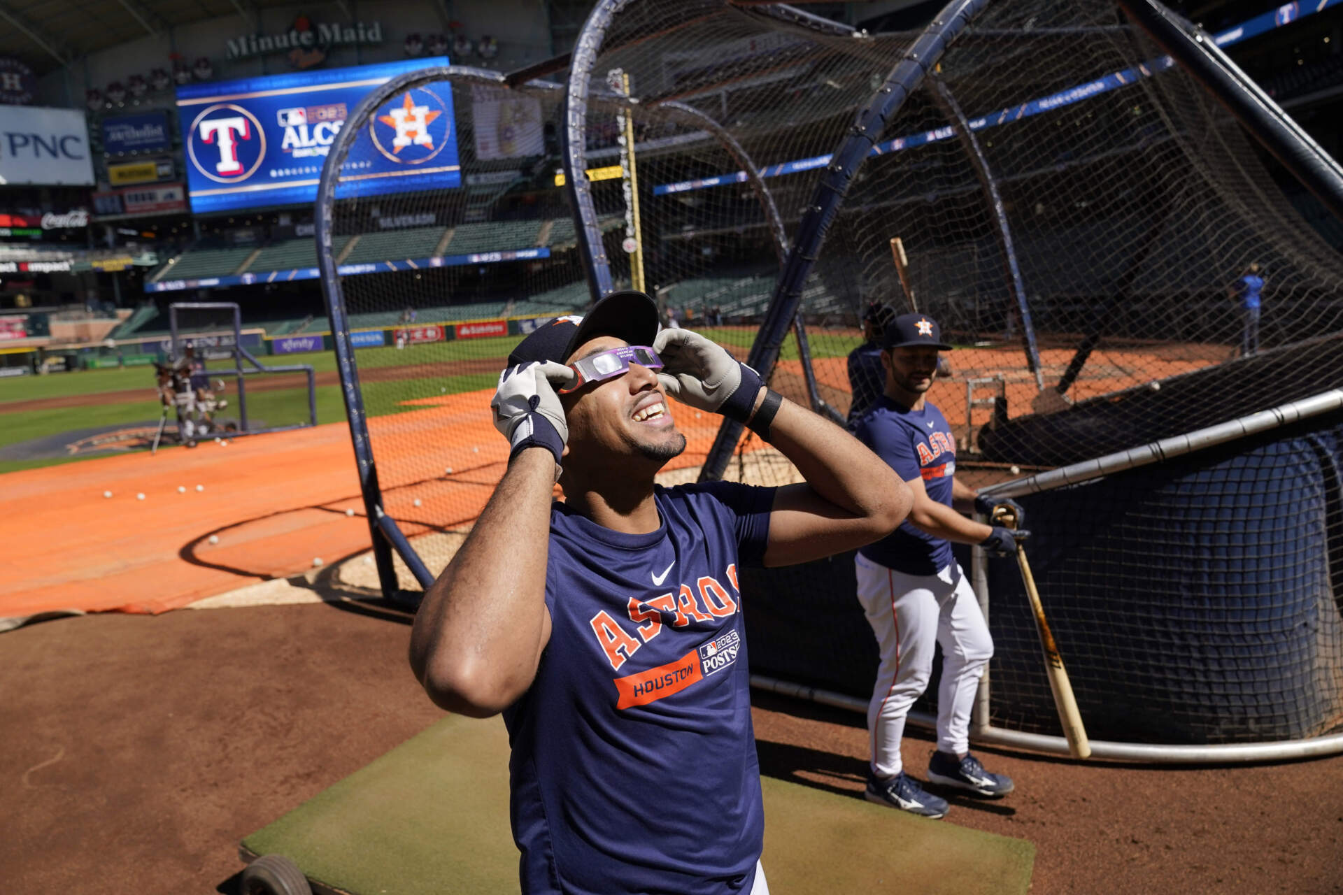 Houston Astros' Dixon Machado wears protective glasses to view the solar eclipse during baseball practice in Houston, Saturday, Oct. 14, 2023. (Tony Gutierrez/AP)