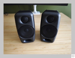 Black rectangular speakers on light wooden surface