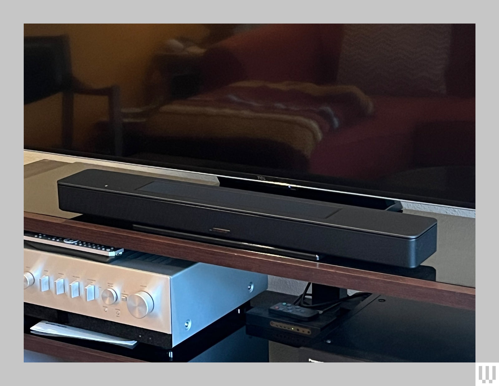 Bose Smart Soundbar a long narrow black device sitting at the base of a large flatscreen tv