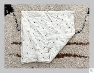 Mushie Muslin Swaddle Blanket in white with a pattern of little illustrated sailboats