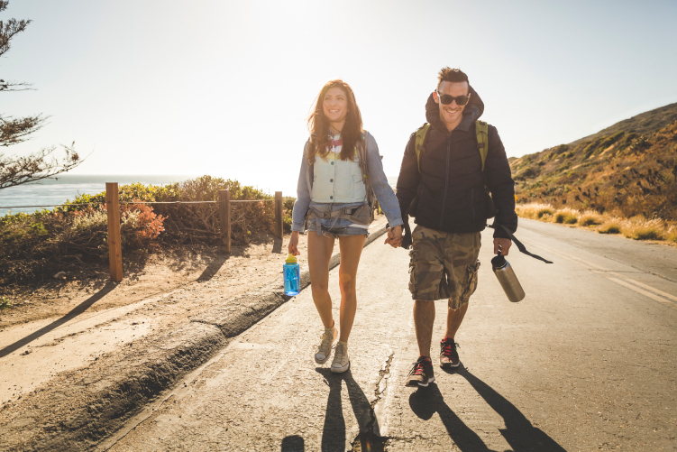 A couple walking hand in hand along a path in front of the ocean