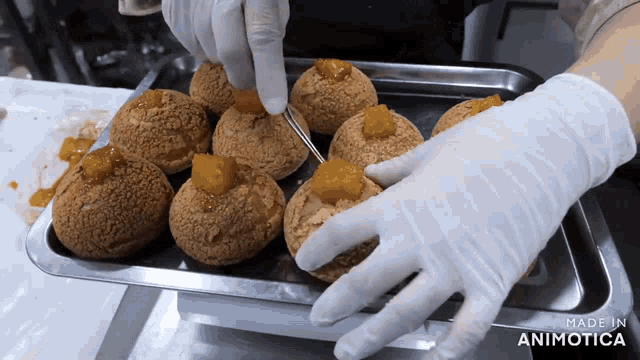 a person wearing white gloves holds a fork over a tray of cupcakes with the words made in animotica visible