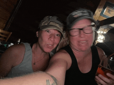 two women are posing for a picture with one wearing a hat that says ' us army '