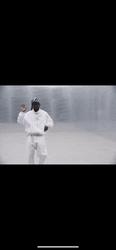 a man in a white jacket and pants is dancing in a white room .