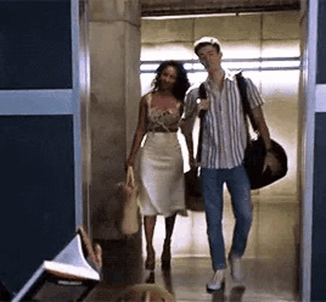 a man and a woman are walking down an elevator together .