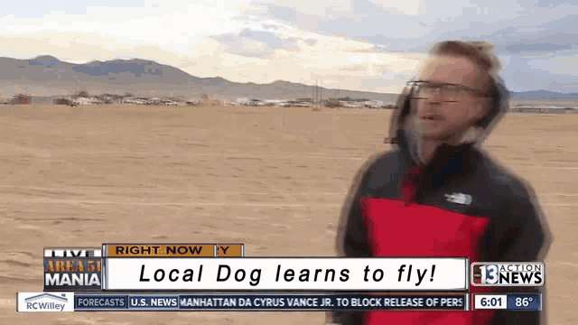 a man in a red jacket is standing in front of a sign that says " local dog learns to fly "