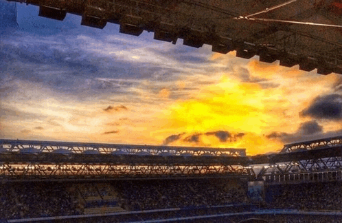 a stadium with a sunset in the background and a few lights on