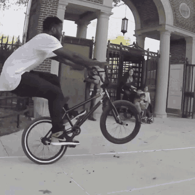 a man is doing a trick on a bike in front of a brick building with a sign on it