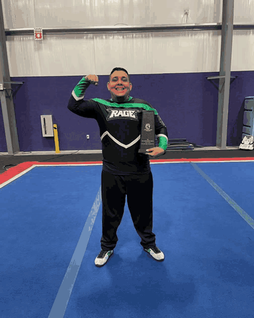 a man in a green and black rage shirt holds a trophy