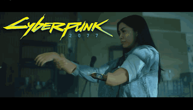 a woman is standing in front of a cyberpunk 2077 poster