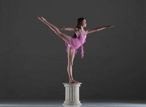 a young woman in a pink dress is balancing on a pillar