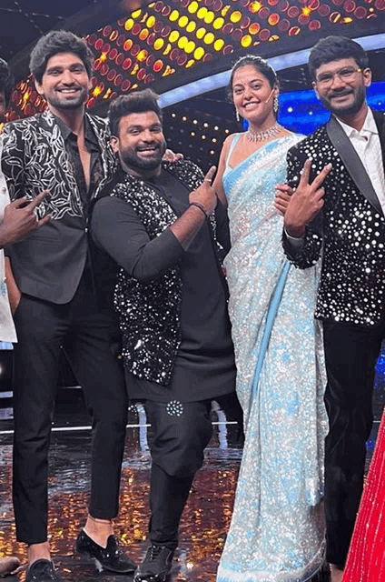 a group of people posing for a picture with one woman wearing a blue saree