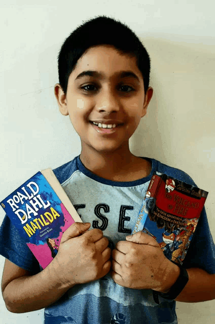 a young boy holds two books in his hands one of which is titled roald dahl matilda