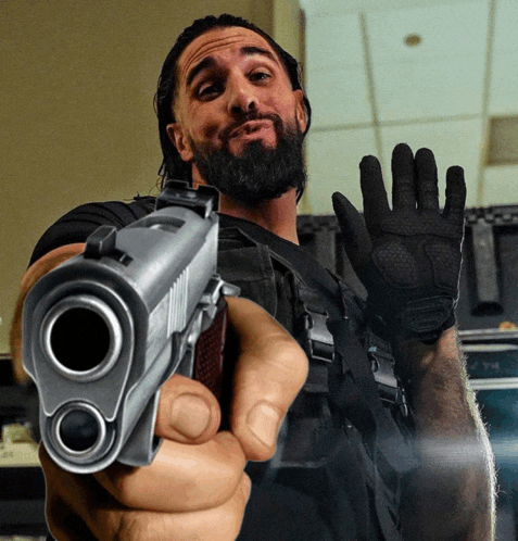 a man with a beard is pointing a gun at the camera while wearing a black glove