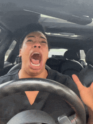 a woman is driving a car and making a funny face