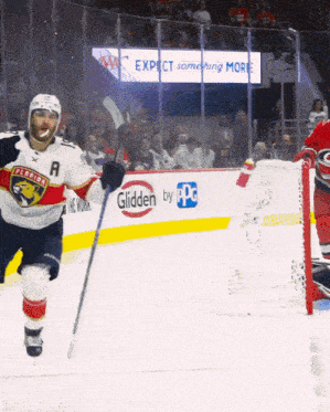 a hockey player wearing a florida panthers jersey stands on the ice in front of a glidden by ppg sign