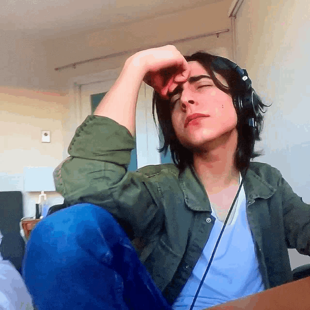 a young man wearing headphones is sitting at a desk with his eyes closed