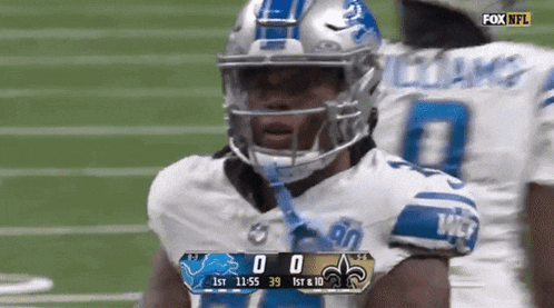 a football player wearing a helmet stands on a field with a scoreboard displaying the score of 0 to 39