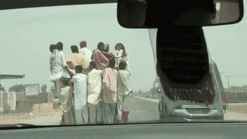 a group of people are standing on top of a car with a license plate that says ' toyota ' on it