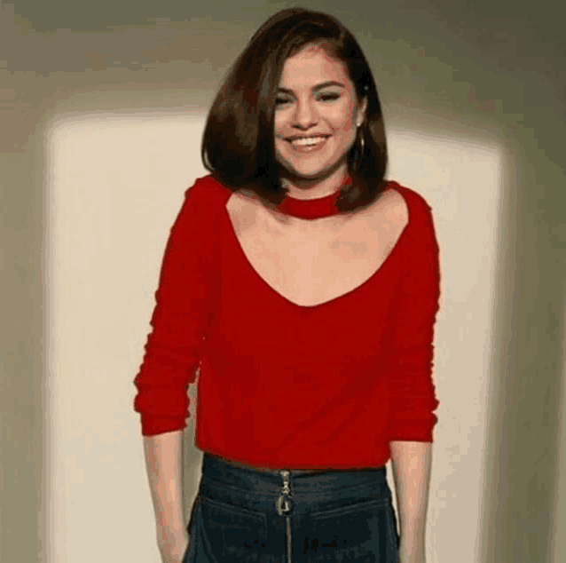 selena gomez is wearing a red sweater and a choker necklace .