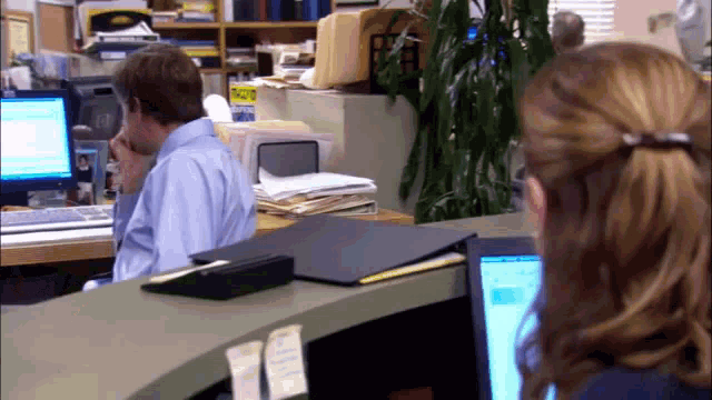 a man sits at a desk in front of a computer with a sign on the wall that says ' priority mail '