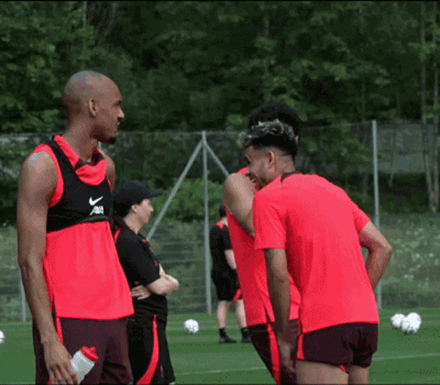 a group of soccer players are standing on a field and one of them is wearing a vest that says nike