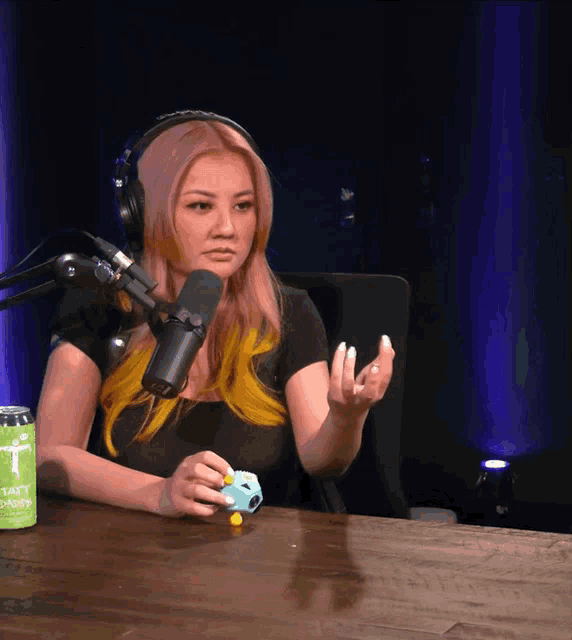 a woman sitting at a table with a microphone and a can that says ' ultimate ears ' on it