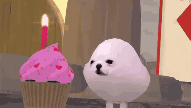 a white seal is standing next to a pink cupcake with a lit candle .