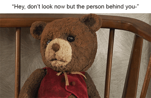 a teddy bear sitting in a chair with the words " hey don 't look now but the person behind you " above it