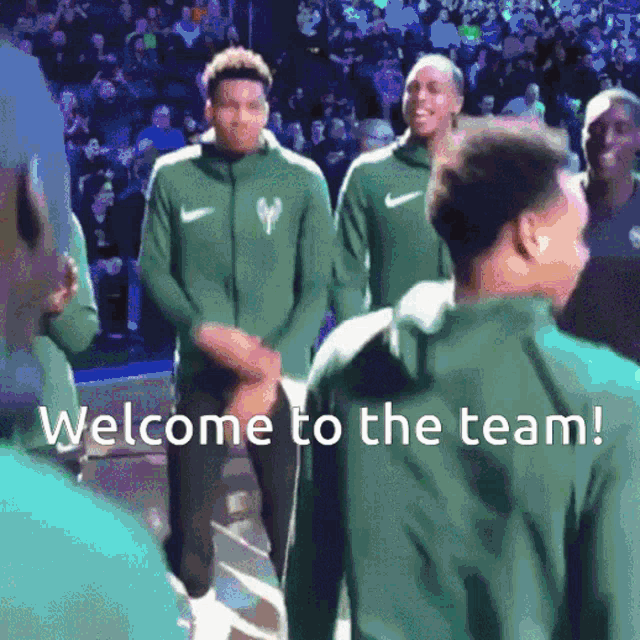 a group of basketball players are standing in front of a crowd with the words welcome to the team below them