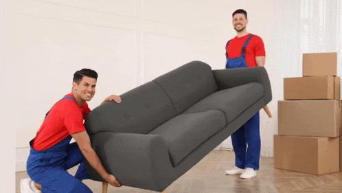 two men are moving a couch in a living room