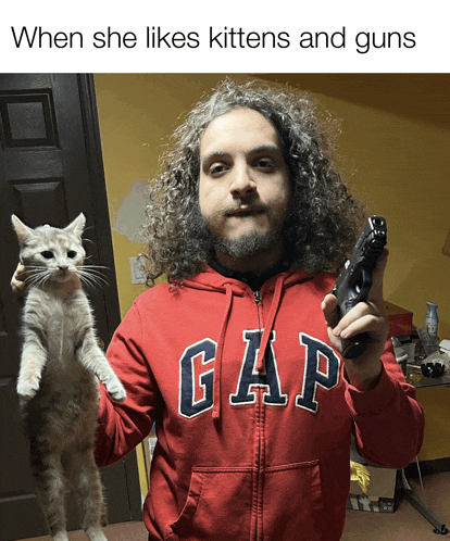 a man holding a cat and a gun wearing a red gap sweatshirt