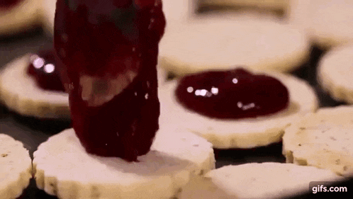 a person is spreading jam on a cookie .