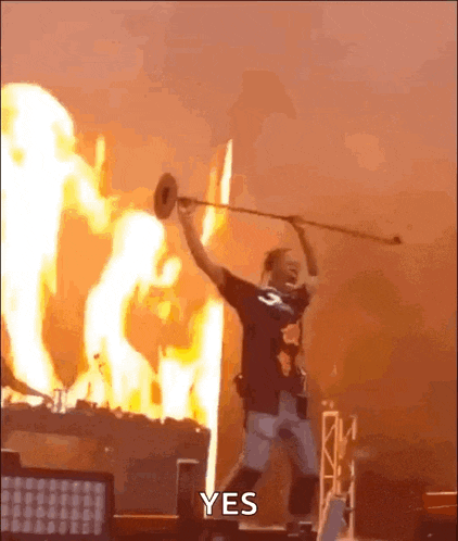 a man is playing a trumpet in front of a fire with the words yes written on the bottom .