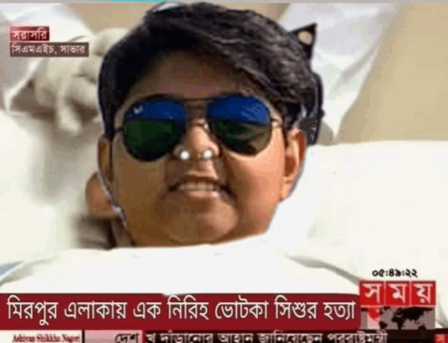 a boy wearing sunglasses is laying in a bed