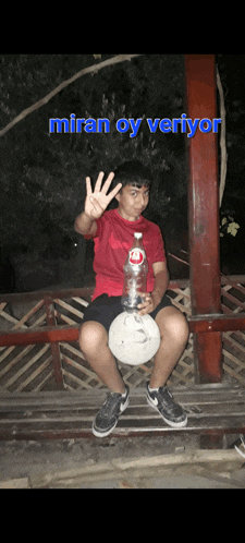 a young boy is sitting on a wooden bench holding a bottle of miran water