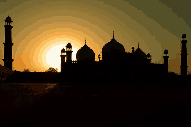 a silhouette of a mosque at sunset with the sun behind it