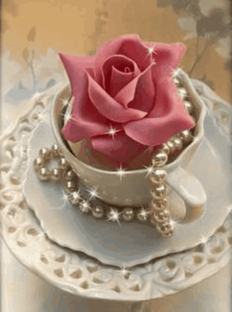 a pink rose is in a cup of tea with pearls .